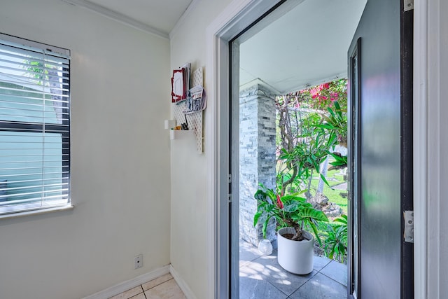 tiled entryway featuring crown molding and baseboards