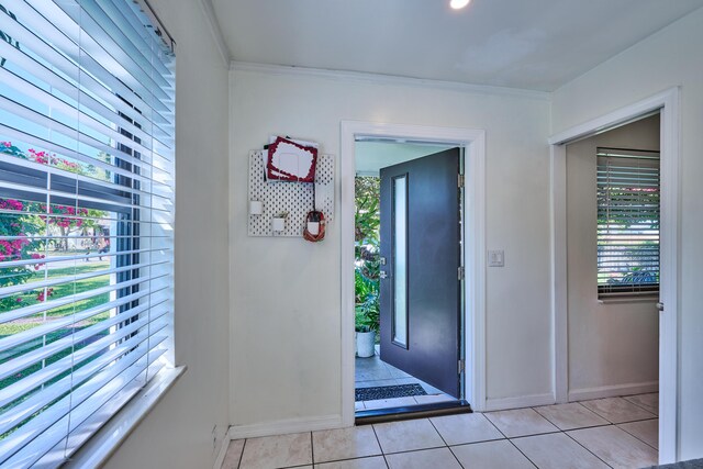 foyer entrance with light tile patterned floors, baseboards, and ornamental molding