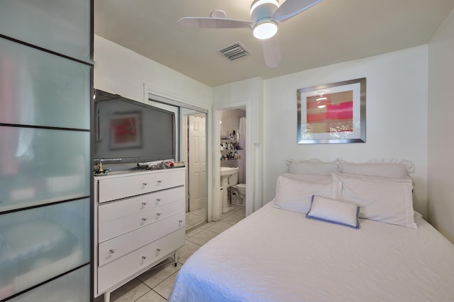 bedroom featuring ensuite bath, light tile patterned floors, visible vents, and ceiling fan