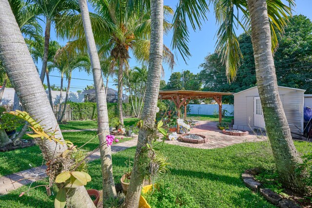 view of yard with a patio, fence, and an outbuilding