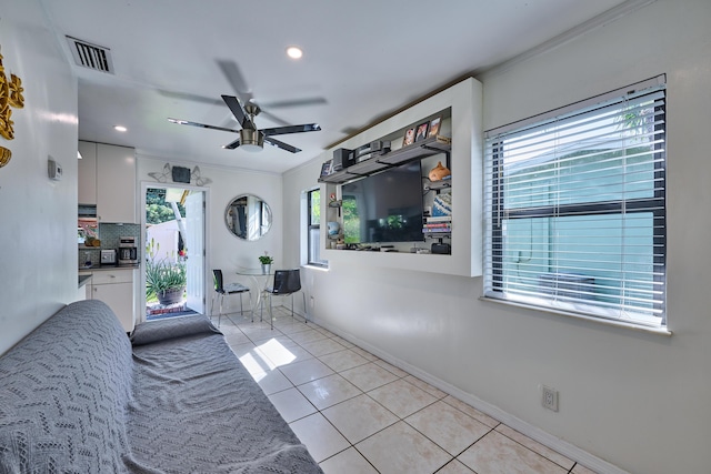 interior space featuring visible vents, a ceiling fan, crown molding, light tile patterned floors, and baseboards