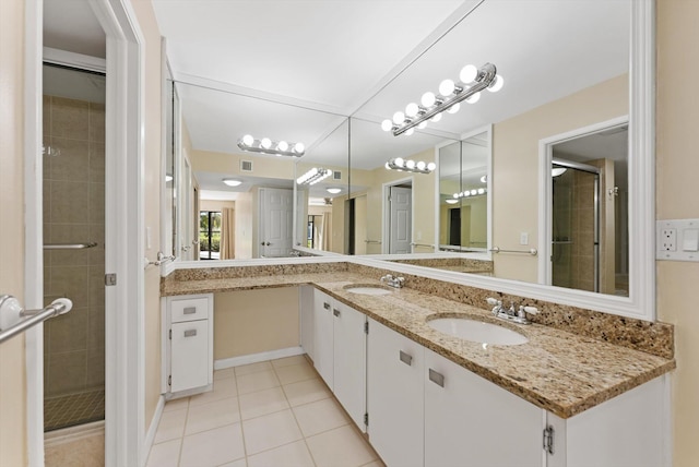 bathroom with tile patterned floors, a stall shower, double vanity, and a sink