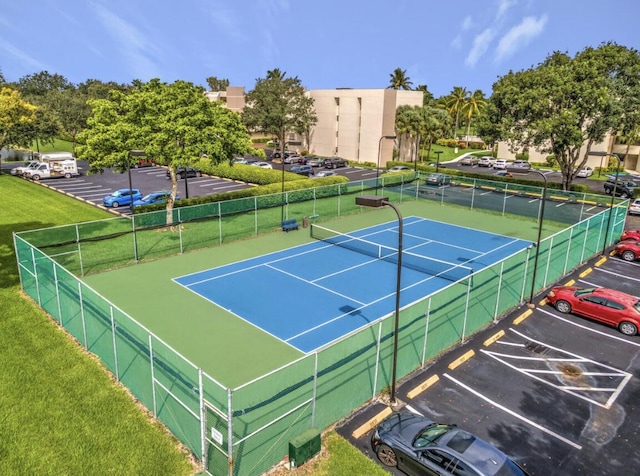 view of tennis court featuring a lawn and fence