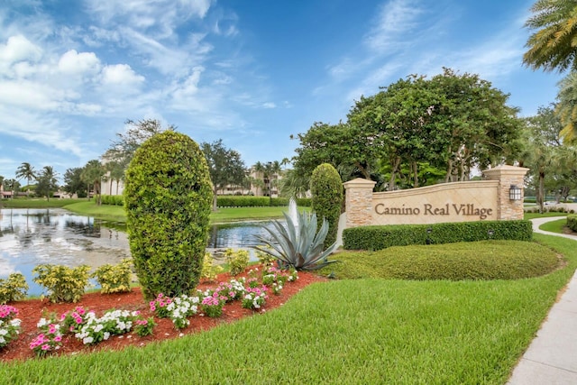 community sign featuring a yard and a water view