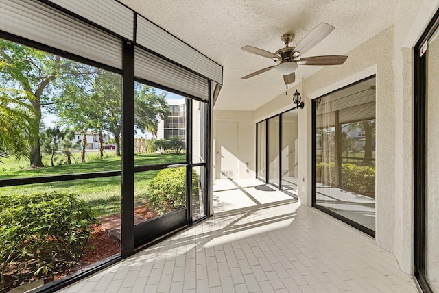 unfurnished sunroom featuring a ceiling fan and a healthy amount of sunlight