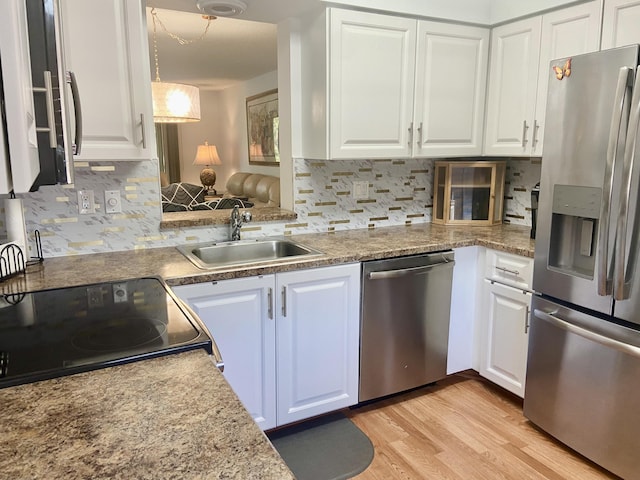 kitchen featuring white cabinets, stainless steel appliances, light wood-type flooring, and a sink