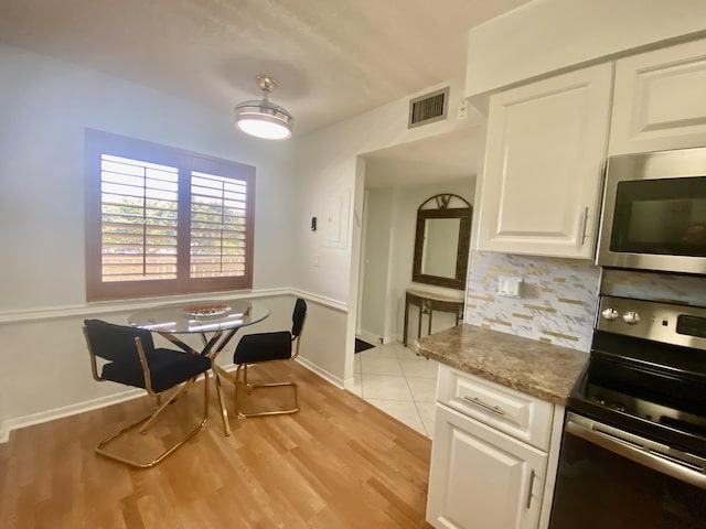 kitchen featuring visible vents, white cabinetry, stainless steel appliances, light wood-style floors, and decorative backsplash