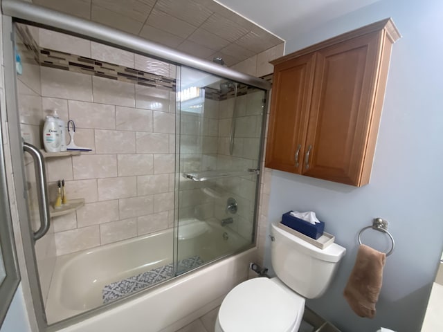 bathroom with toilet and shower / bath combination with glass door