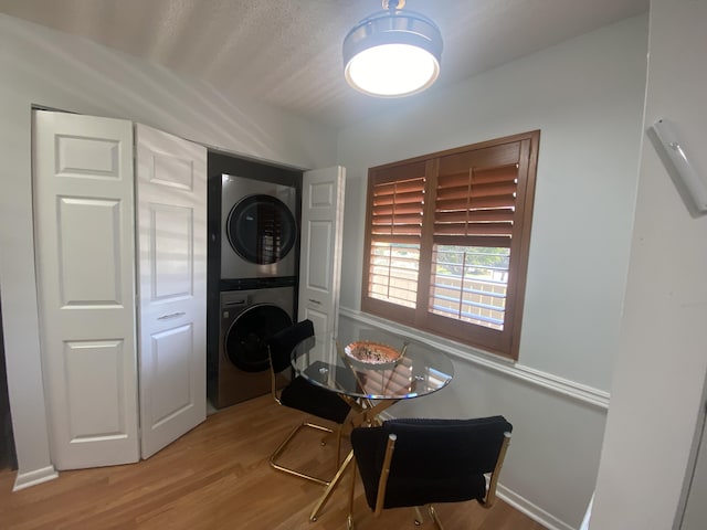 washroom featuring laundry area, stacked washing maching and dryer, and wood finished floors