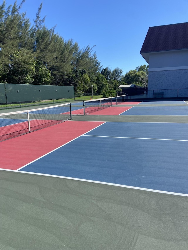 view of tennis court with community basketball court and fence