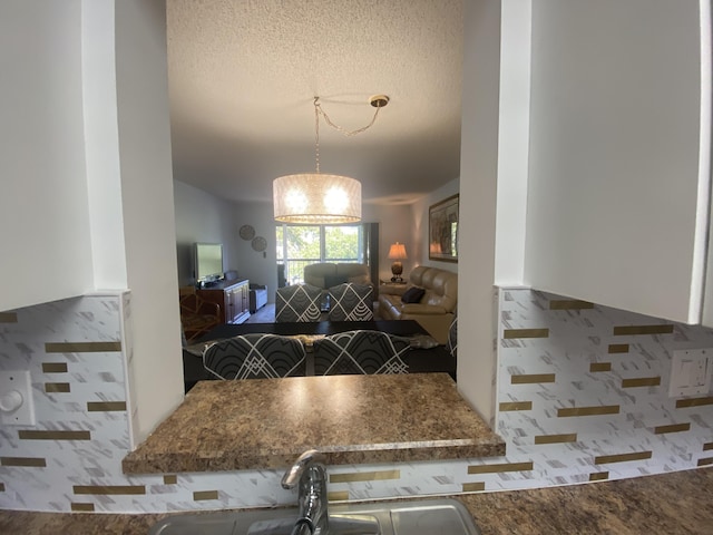 kitchen featuring a sink, decorative light fixtures, a textured ceiling, and open floor plan
