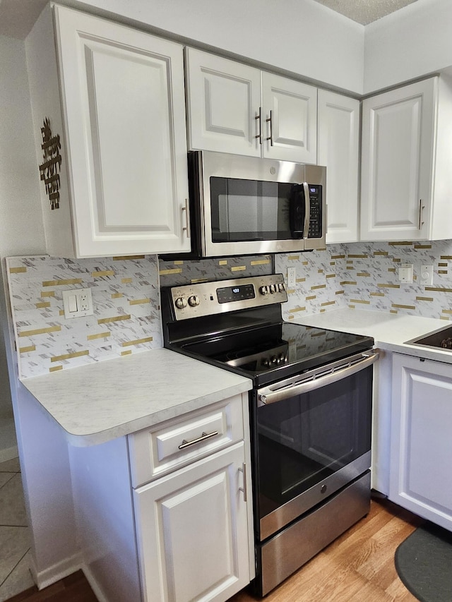 7185 Huntington Ln Unit 405, Delray Beach, FL 33446 - kitchen with appliances with stainless steel finishes, light countertops, backsplash, white cabinets, and light wood-style flooring