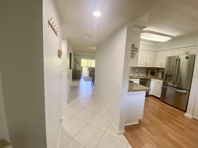 hall with light wood-style floors and baseboards