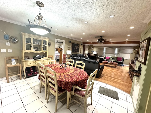 dining space featuring light tile patterned floors, a textured ceiling, a ceiling fan, and ornamental molding