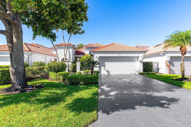 mediterranean / spanish home featuring a front lawn, a tile roof, stucco siding, decorative driveway, and a garage