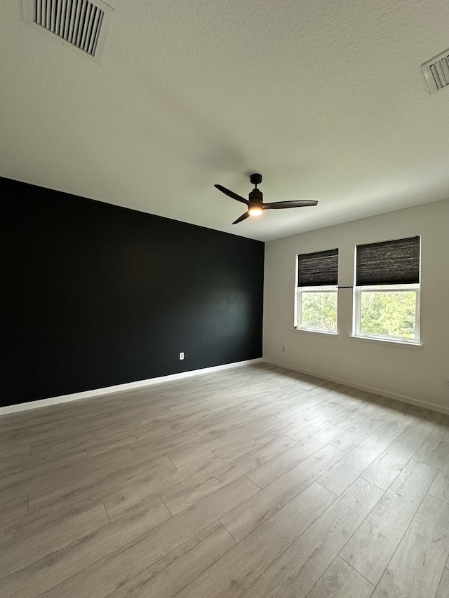 unfurnished room featuring visible vents, baseboards, a ceiling fan, and light wood finished floors