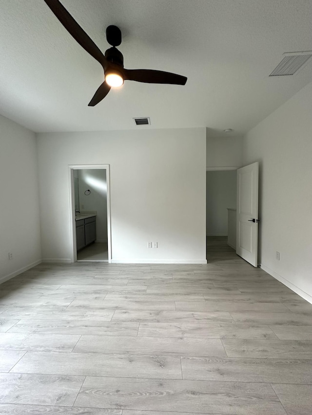 unfurnished bedroom featuring light wood finished floors, visible vents, ensuite bath, and ceiling fan