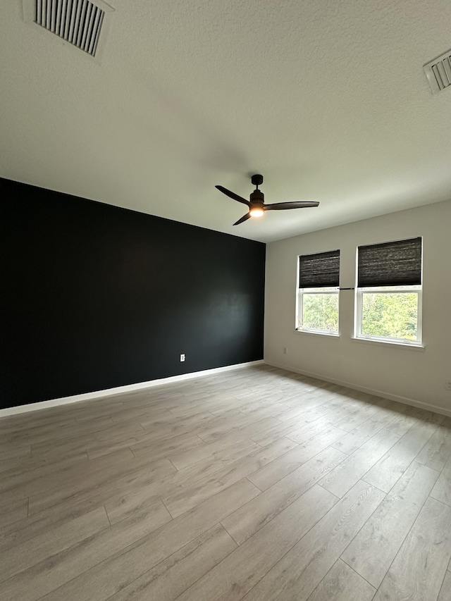 unfurnished room featuring light wood finished floors, baseboards, visible vents, and ceiling fan