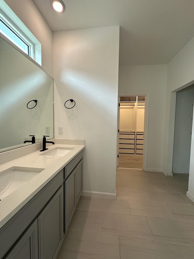 full bath featuring double vanity, a sink, and baseboards