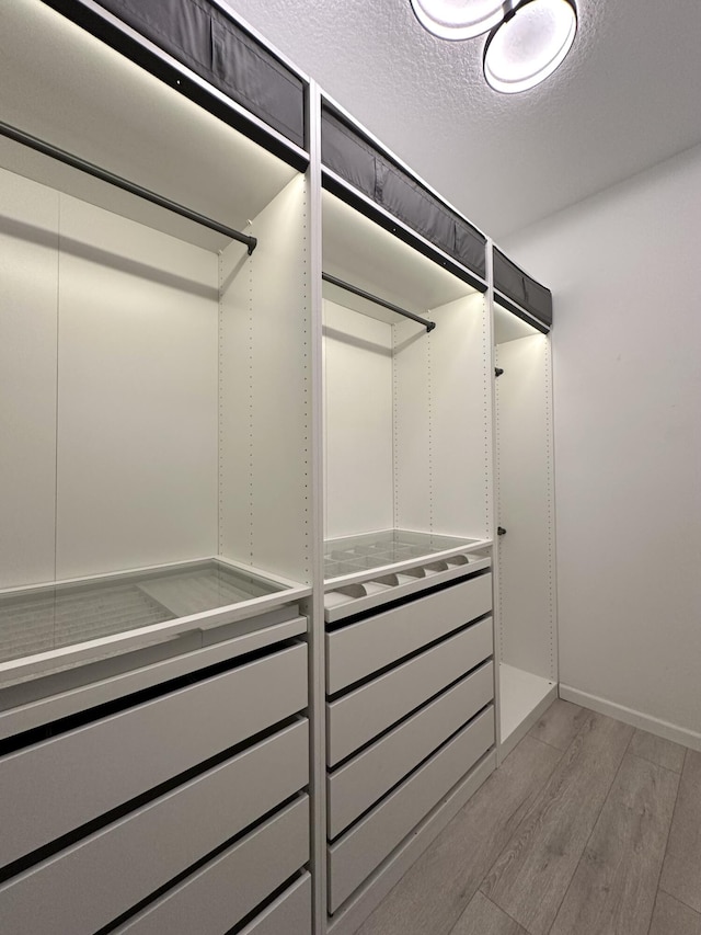 walk in closet with light wood finished floors