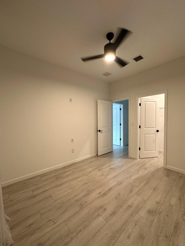unfurnished bedroom featuring baseboards, visible vents, light wood-style floors, and a ceiling fan