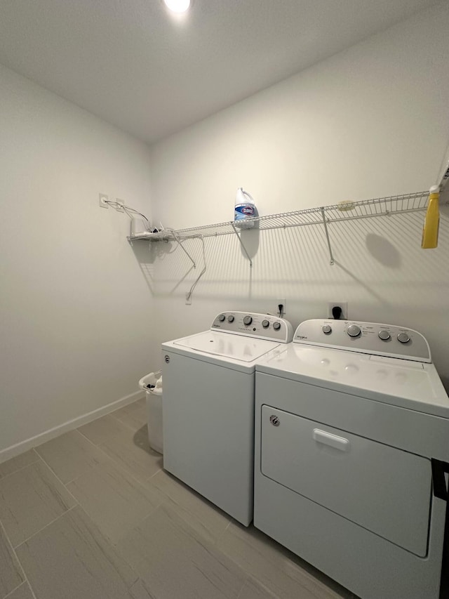 clothes washing area with baseboards, washing machine and dryer, and laundry area