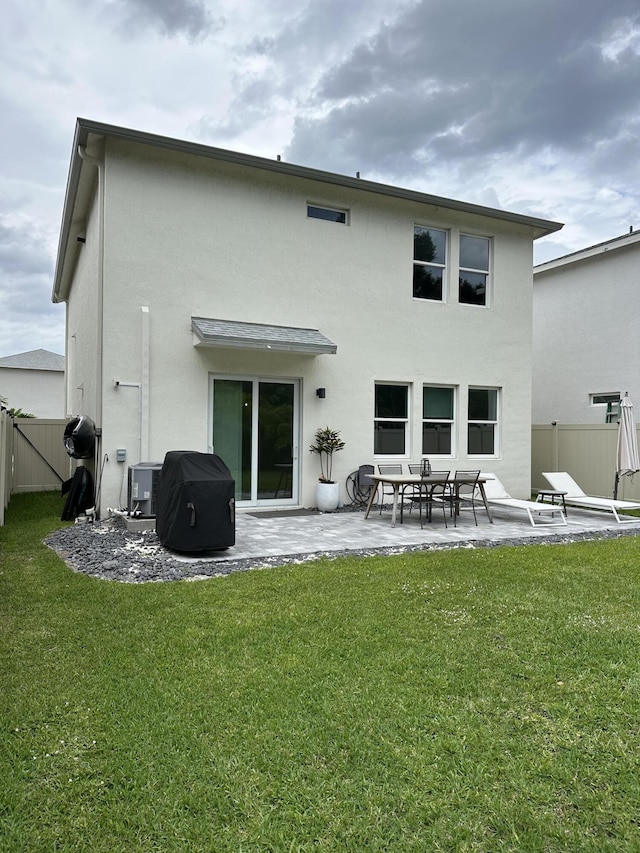 back of house with central air condition unit, stucco siding, fence, a patio, and a lawn