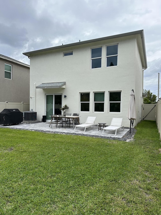 back of property featuring a gate, stucco siding, a fenced backyard, a patio, and a yard