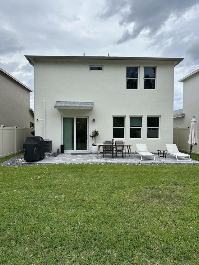 back of house with a lawn, fence, a patio, and stucco siding