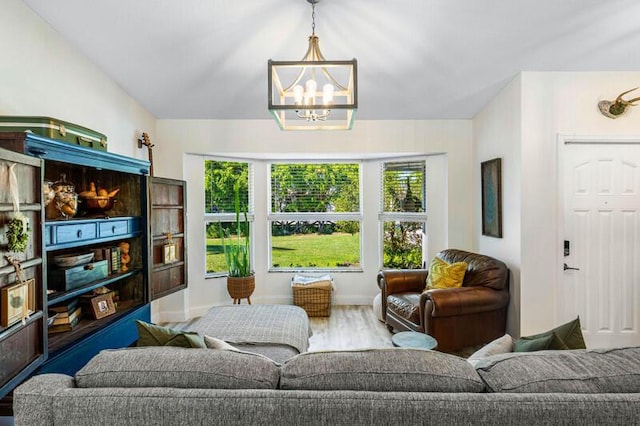 living area featuring vaulted ceiling, baseboards, an inviting chandelier, and wood finished floors