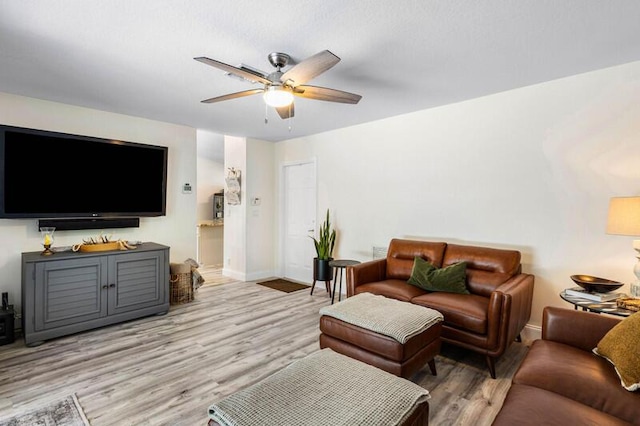 living room featuring a ceiling fan, baseboards, and light wood finished floors