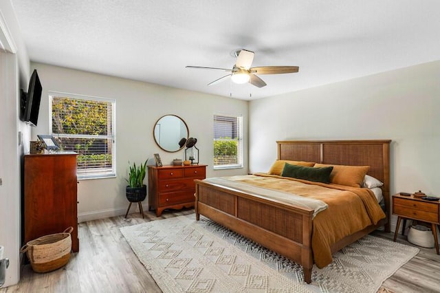 bedroom featuring multiple windows, baseboards, and light wood finished floors