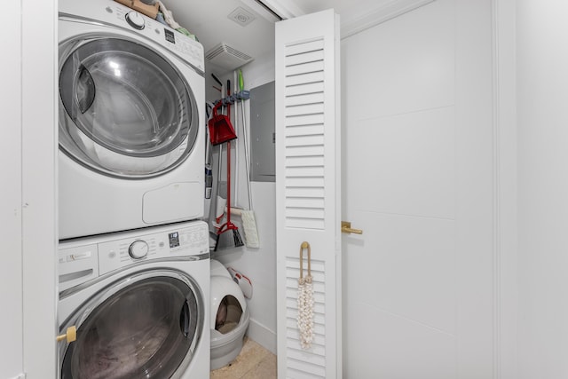 clothes washing area featuring laundry area, electric panel, and stacked washer / drying machine