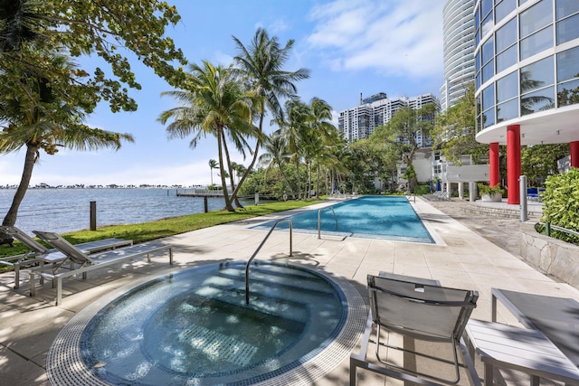 community pool with a patio, a water view, and a hot tub