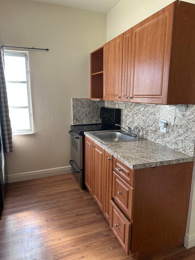 kitchen featuring a sink, open shelves, stainless steel electric stove, backsplash, and light wood finished floors