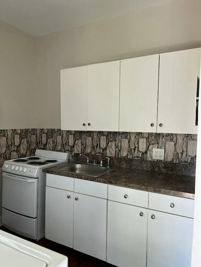 kitchen featuring a sink, dark countertops, white cabinets, and white range with electric stovetop