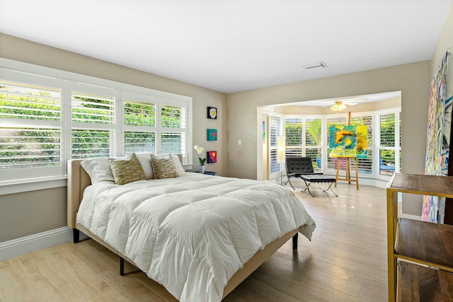 bedroom featuring baseboards, multiple windows, wood finished floors, and access to exterior