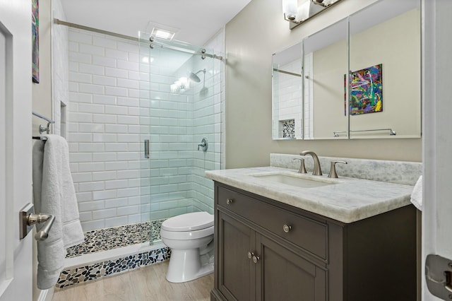 full bathroom with a stall shower, toilet, wood finished floors, and vanity