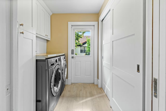 laundry room featuring separate washer and dryer, cabinet space, and light wood-type flooring