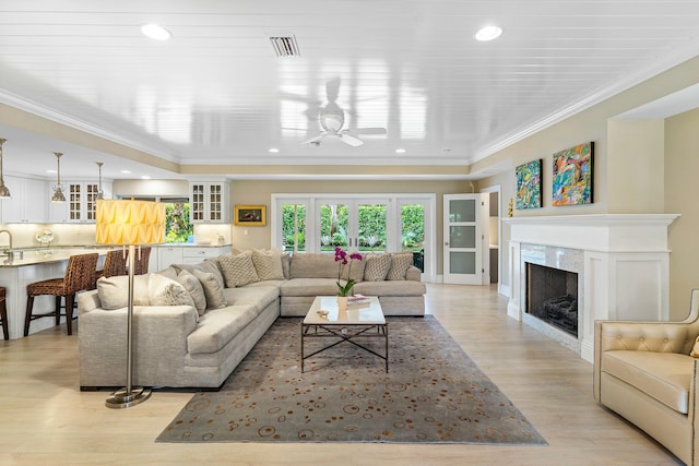 living area featuring visible vents, a fireplace, recessed lighting, light wood-style floors, and crown molding