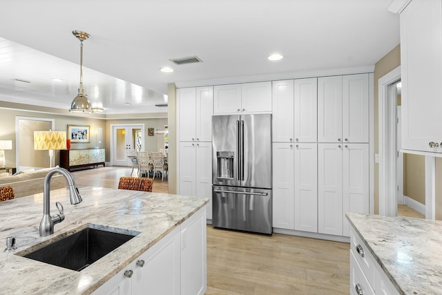 kitchen featuring high end fridge, a sink, white cabinets, decorative light fixtures, and open floor plan