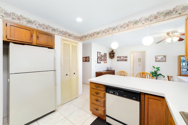 kitchen with white appliances, light tile patterned floors, brown cabinetry, light countertops, and pendant lighting