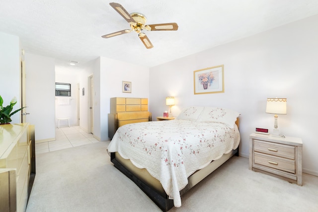 bedroom featuring light tile patterned floors, light carpet, a ceiling fan, and ensuite bathroom