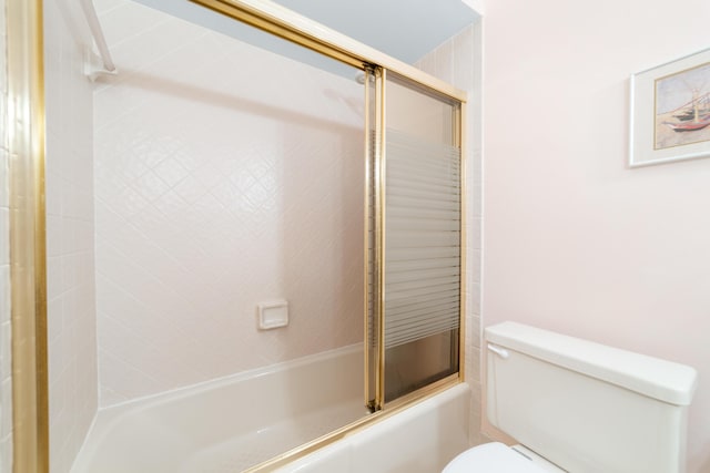 bathroom featuring toilet and combined bath / shower with glass door