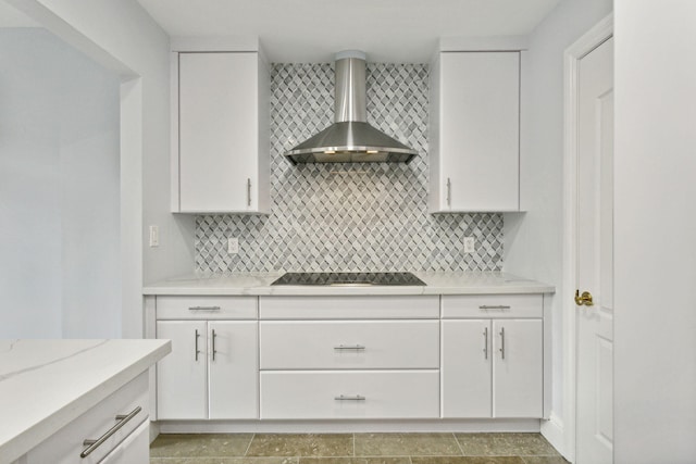 kitchen with stovetop, tasteful backsplash, white cabinets, and wall chimney range hood