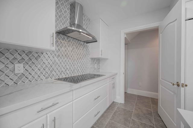 kitchen with decorative backsplash, wall chimney range hood, black electric stovetop, and white cabinets