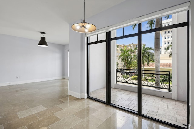 spare room featuring stone tile floors and baseboards