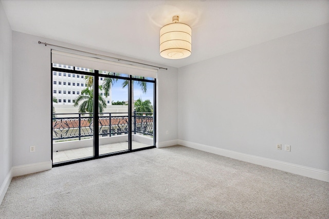 carpeted empty room featuring baseboards