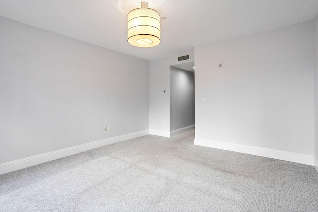 unfurnished room featuring visible vents, light colored carpet, and baseboards