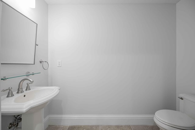 half bath with a sink, baseboards, and toilet